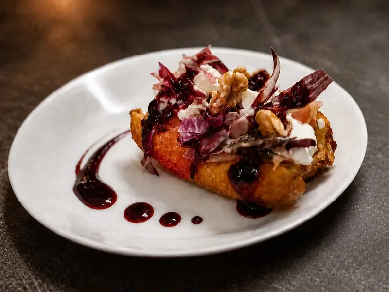 Il Crocchè Mirtilla nel piatto bianco, con radicchio, noci, stracciatella e salsa di mirtilli