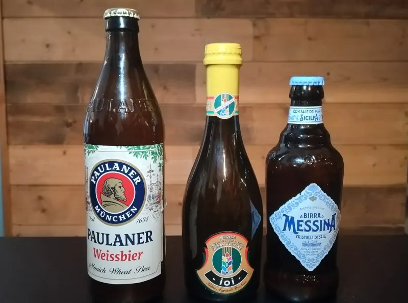 Tre birre in bottiglia sul bancone del locale, davanti alla parete di legno