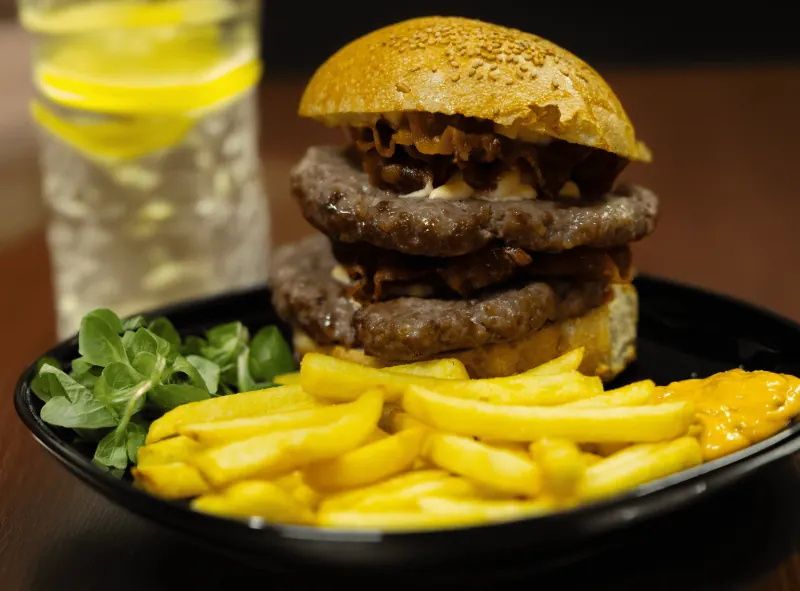 Burger con due hamburger e bacon, patatine e salsa cheddar